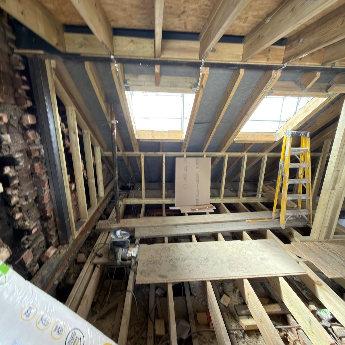 Interior of a loft conversion in Enfield showing installed skylights and the timber roof structure during construction.