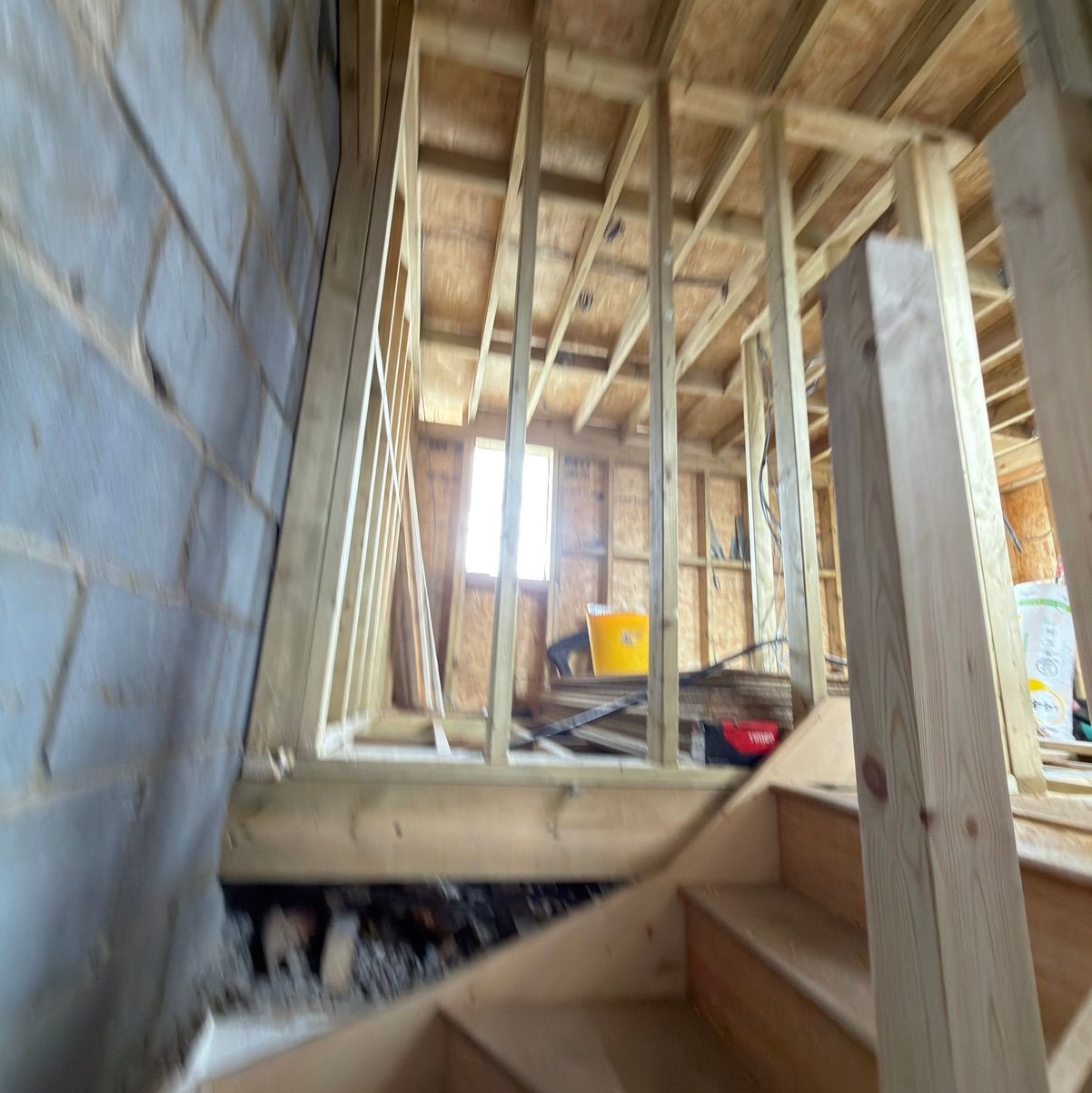 Unfinished interior space under construction, showing wooden framing and stairs for a loft conversion